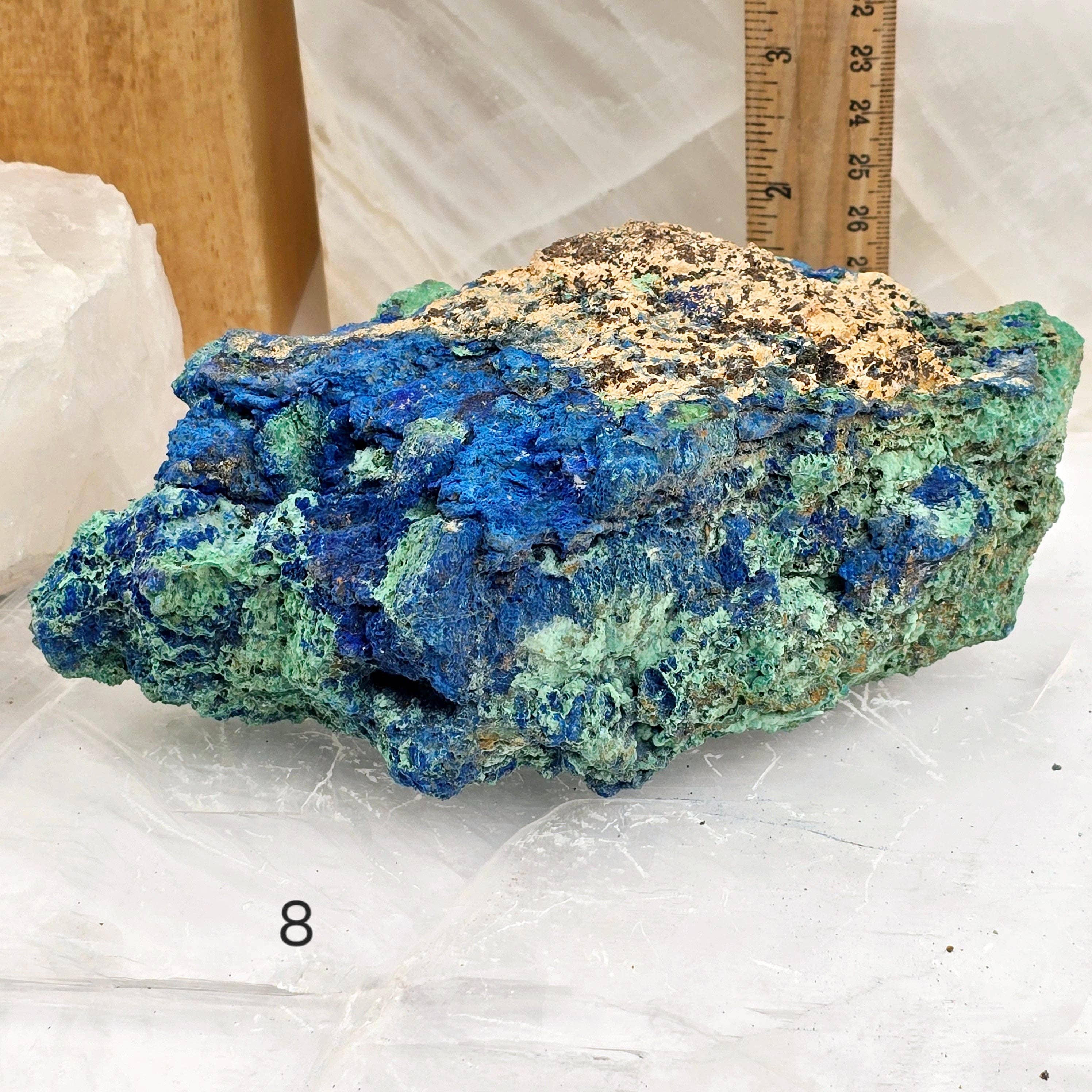 Blue and green mineral specimen on a white surface with a ruler for scale.