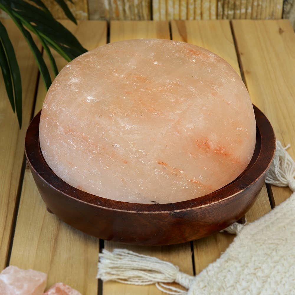 Himalayan salt lamp on a wooden surface with a plant in the background