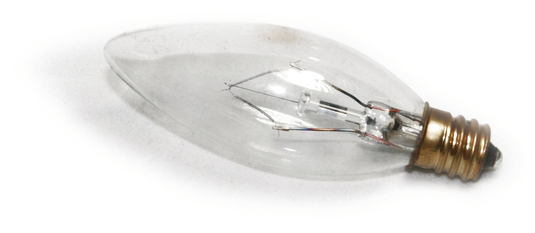 Clear light bulb with a brass base on a white background