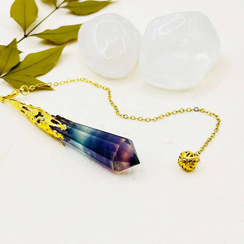 Necklace with a purple crystal pendant on a white surface with leaves in the background