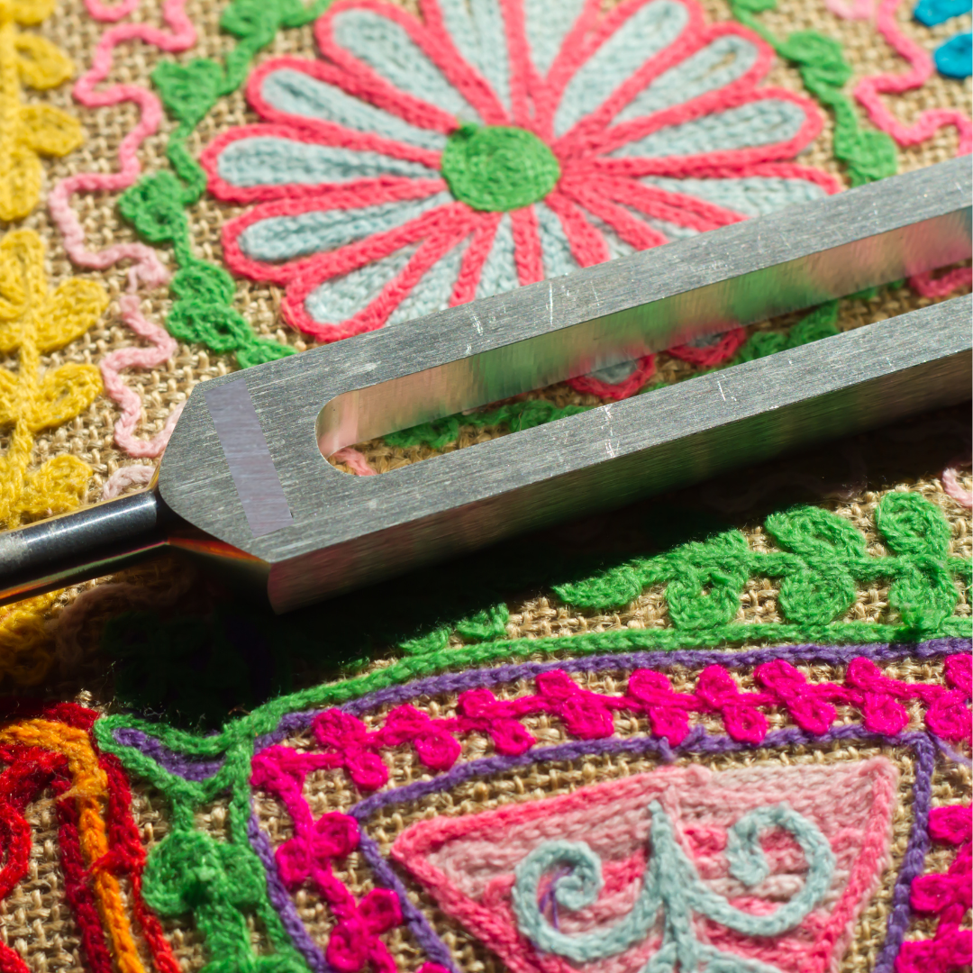 Tuning fork on a colorful embroidered fabric background