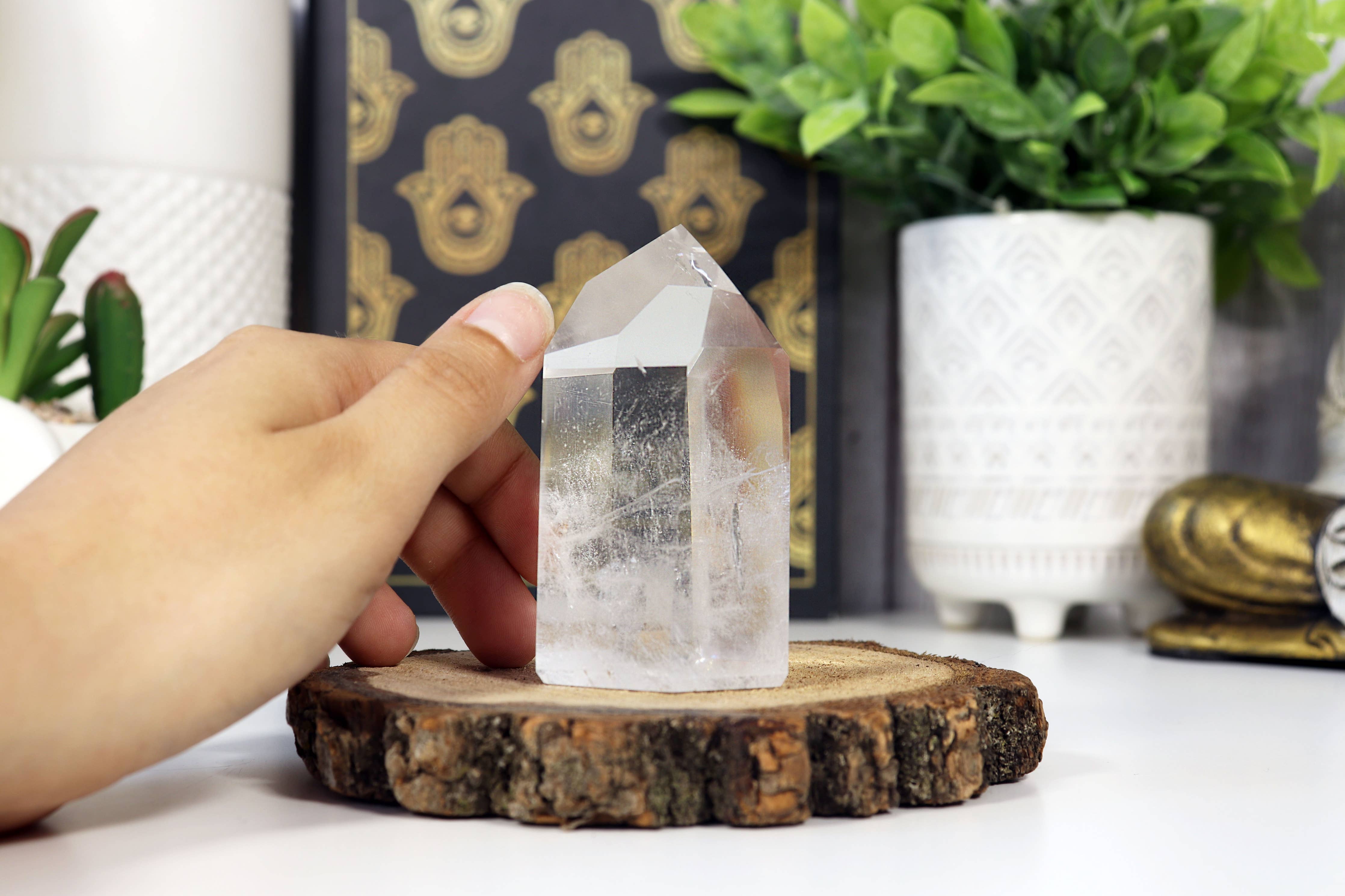 Person holding a crystal on a wooden stand with decorative items in the background
