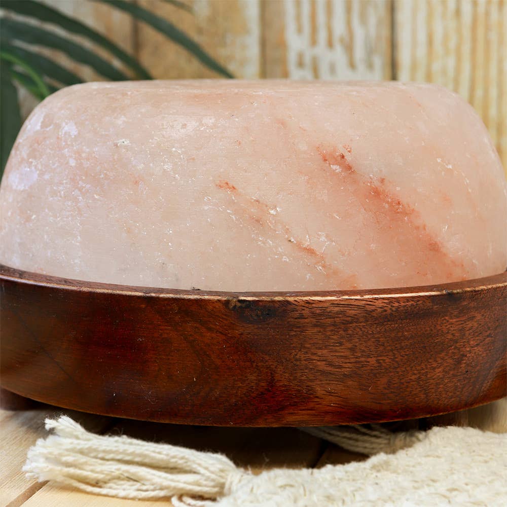Himalayan salt lamp with wooden base on a neutral background