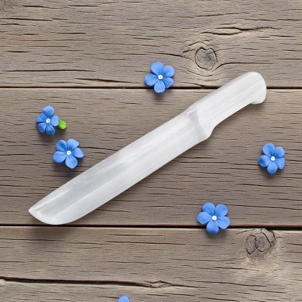 White knife on a wooden surface with blue flowers around it