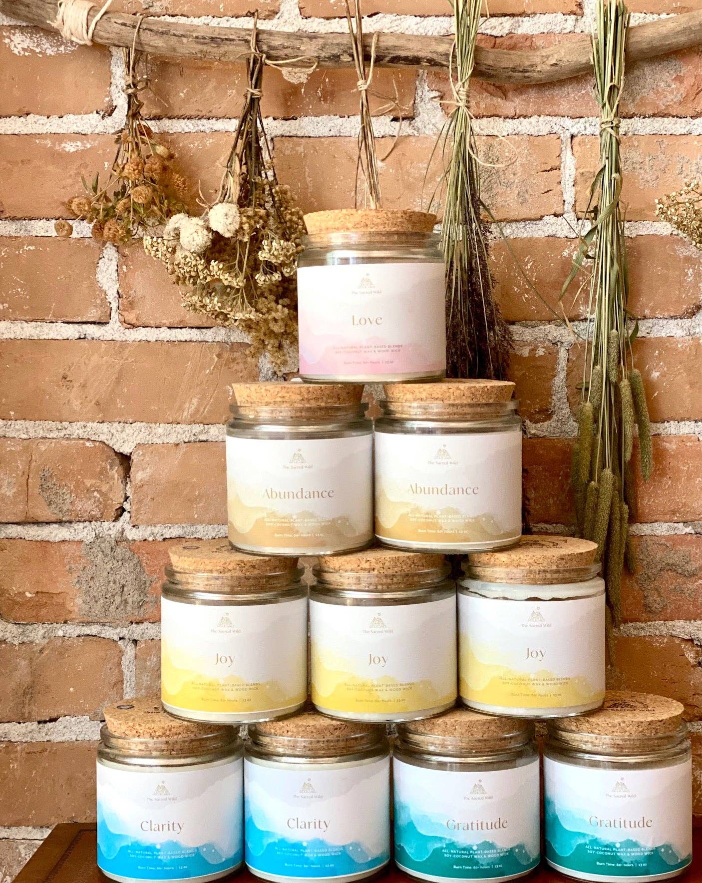 Stack of candles with visible labels against a brick wall background