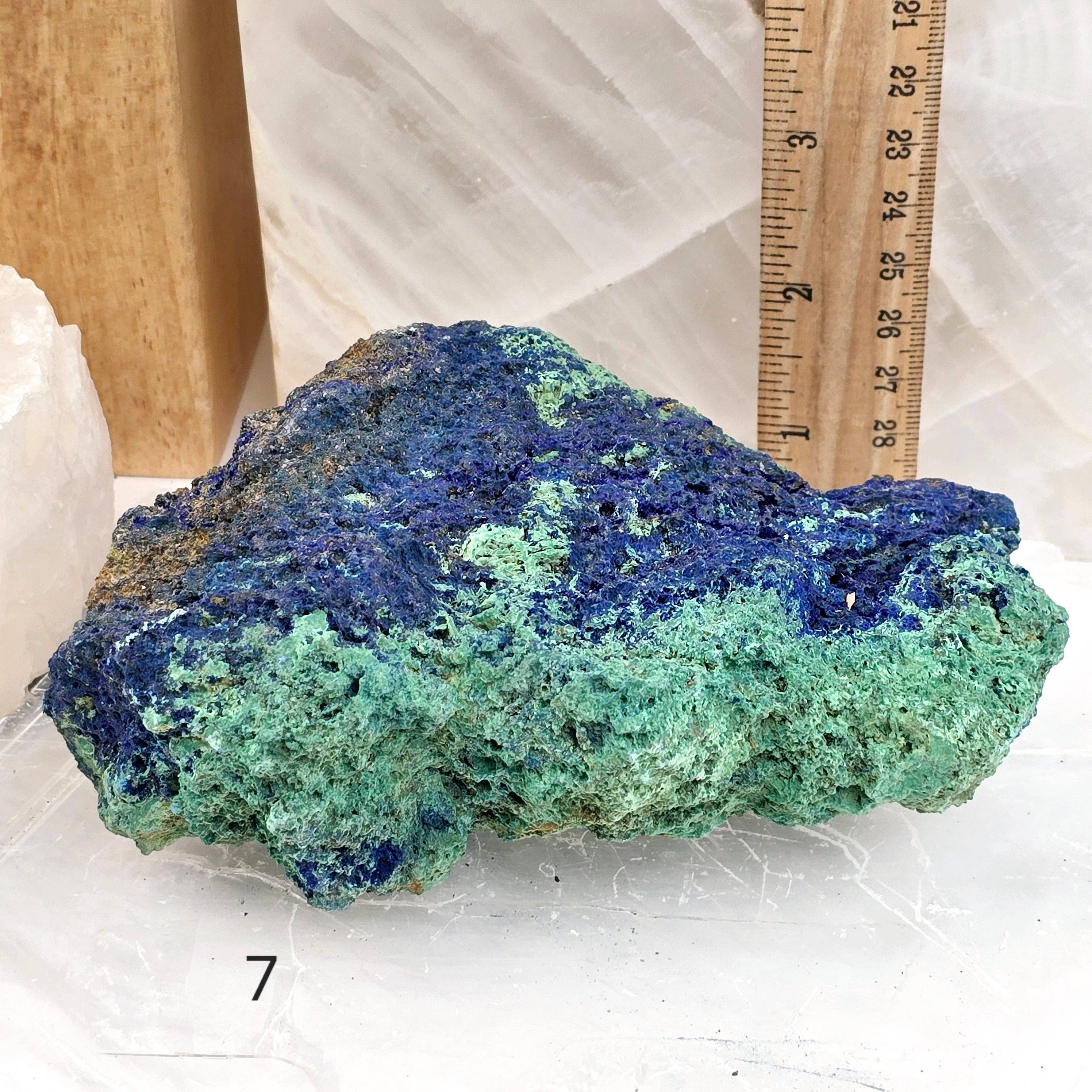 Blue and green mineral specimen with a ruler for scale on a white background