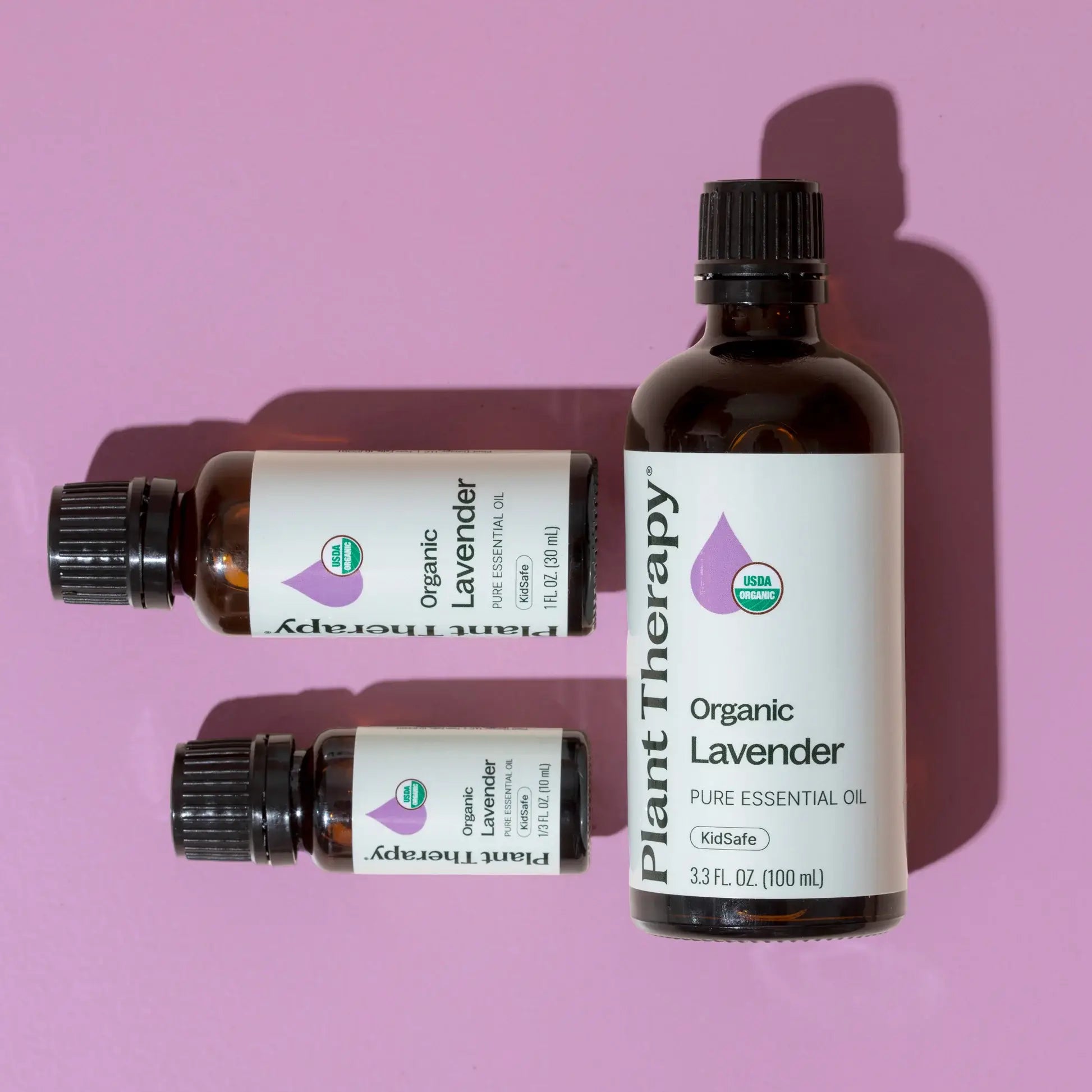 Three bottles of Plant Therapy Organic Lavender essential oil on a pink background
