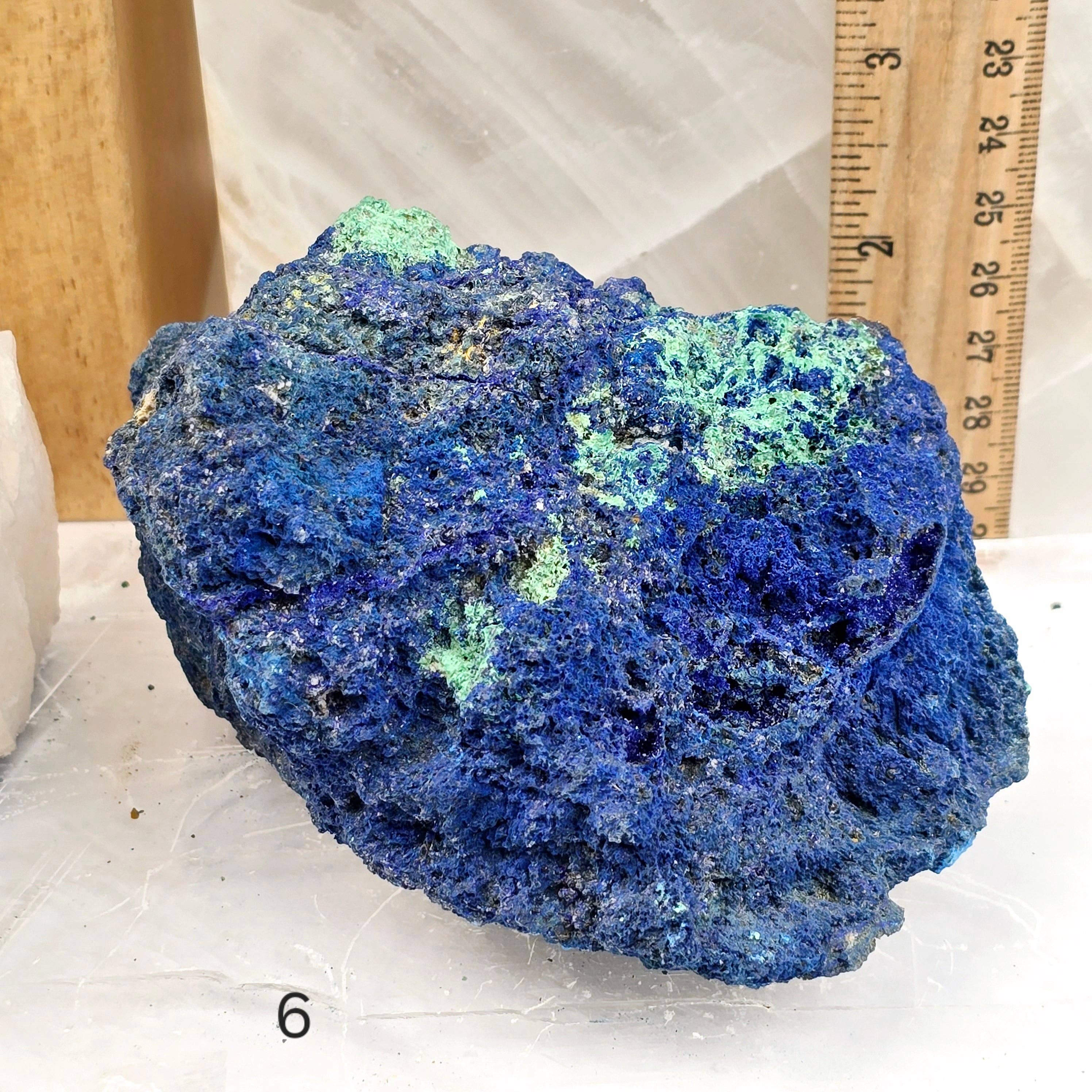 Blue and green mineral specimen with a ruler for scale on a white background