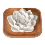 White ceramic lotus flower on a wooden tray