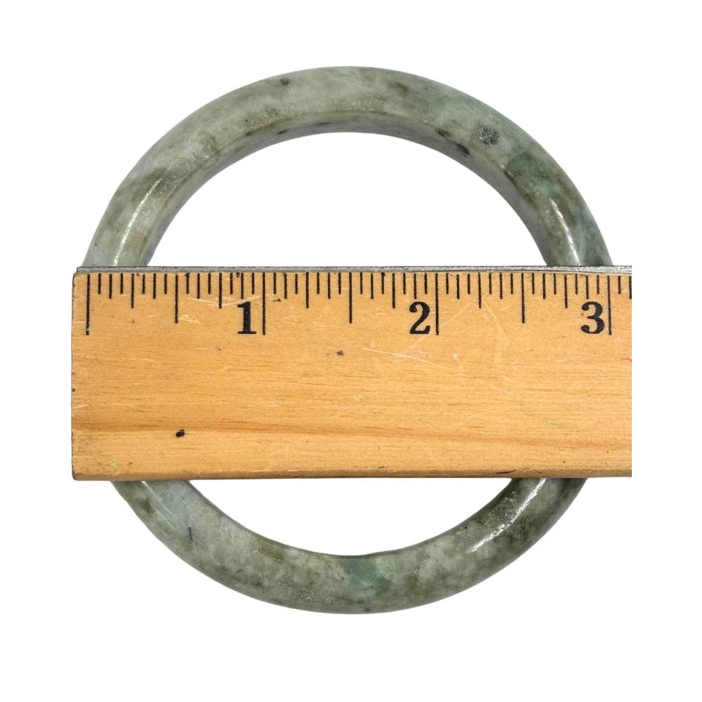 Metal ring with a wooden ruler for scale on a white background