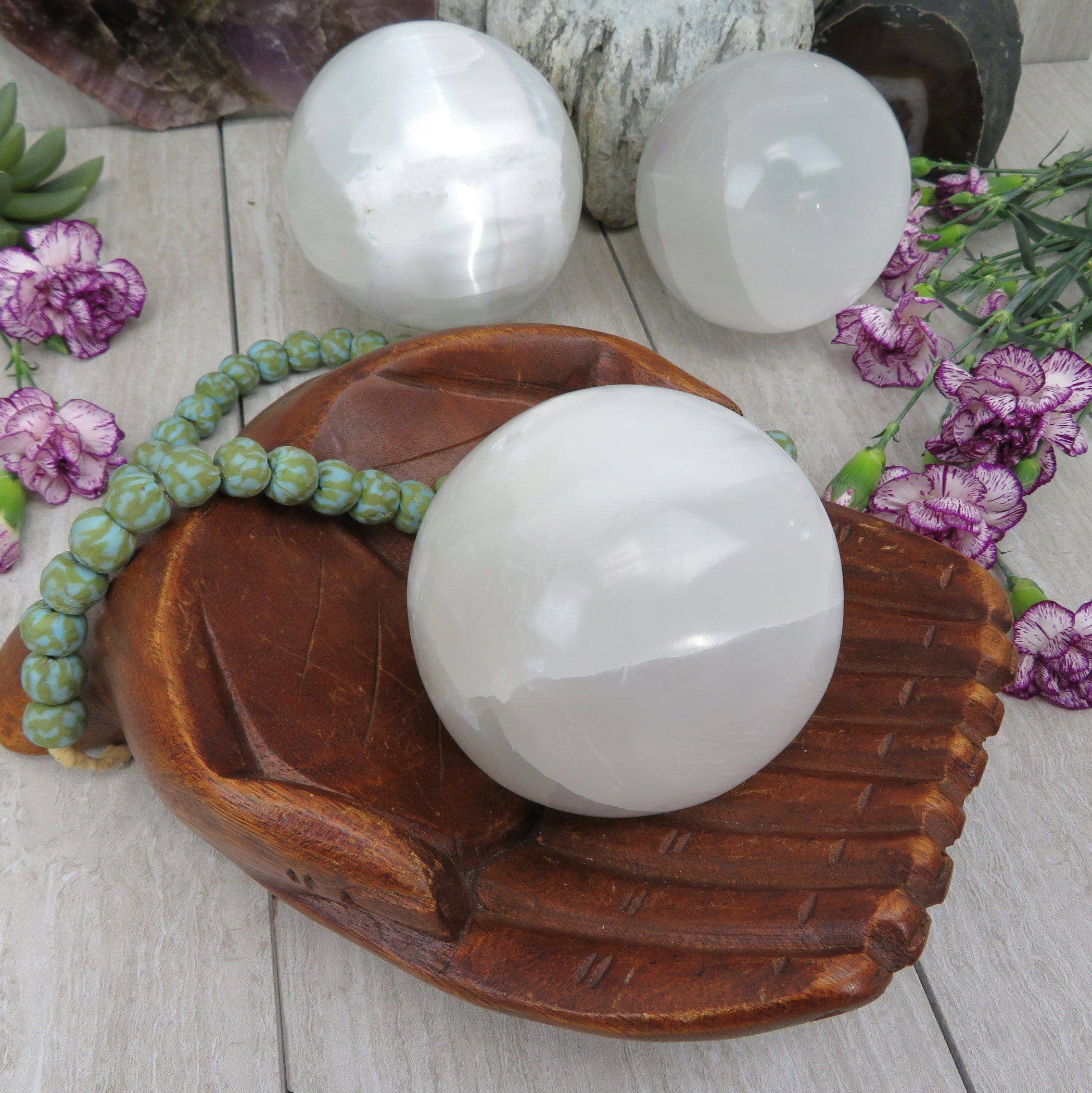 White crystal balls on a wooden base with flowers around