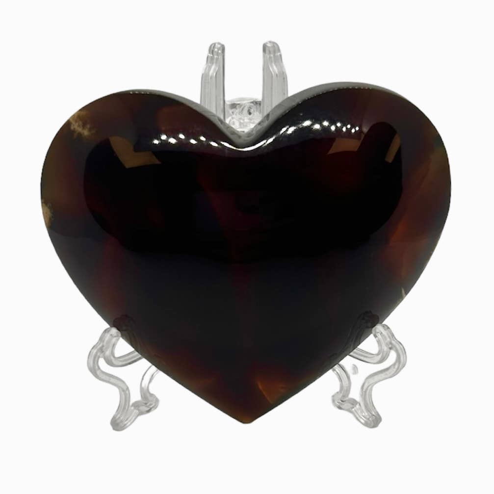 Heart-shaped tortoiseshell pendant on a clear stand against a white background