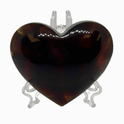 Heart-shaped tortoiseshell pendant on a clear stand against a white background