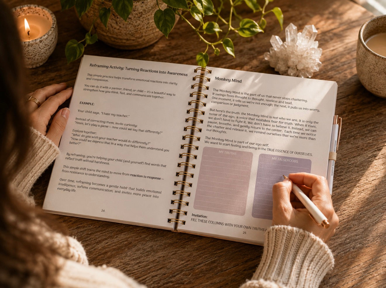 A person sits at a wooden table writing in an open spiral notebook. The notebook pages show guided journaling prompts and reflection prompts, with lavender-colored sticky notes.