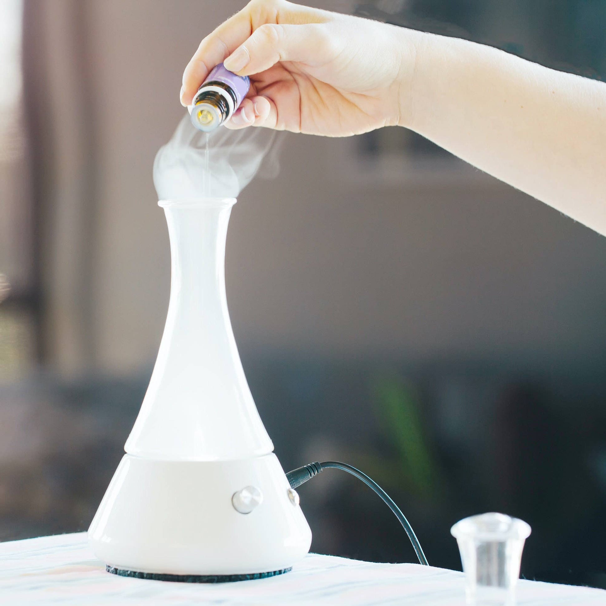 Hand replacing a light bulb in a white lamp with a blurred background - JOY - Journey Of You - Spiritual, Holistic, Empowering
