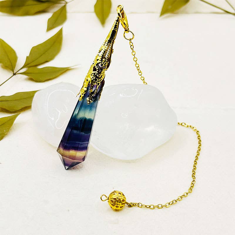 Decorative object with a gold chain and geometric design on a white surface with green leaves.