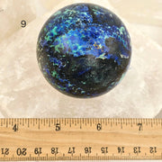 Multicolored spherical object on a white background with a ruler for scale.