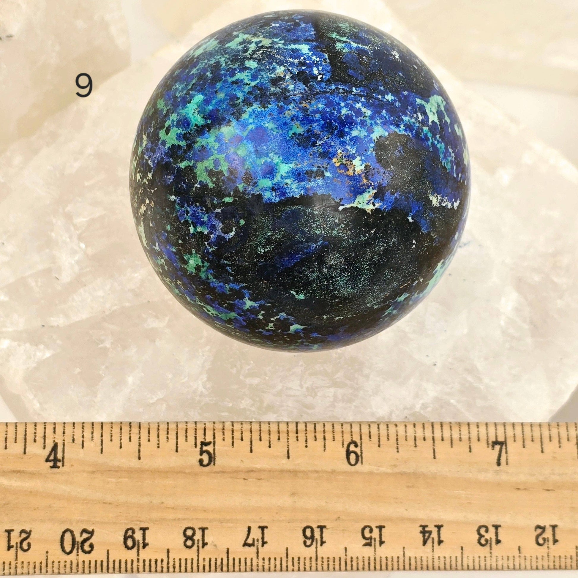 Multicolored spherical object on a white background with a ruler for scale.