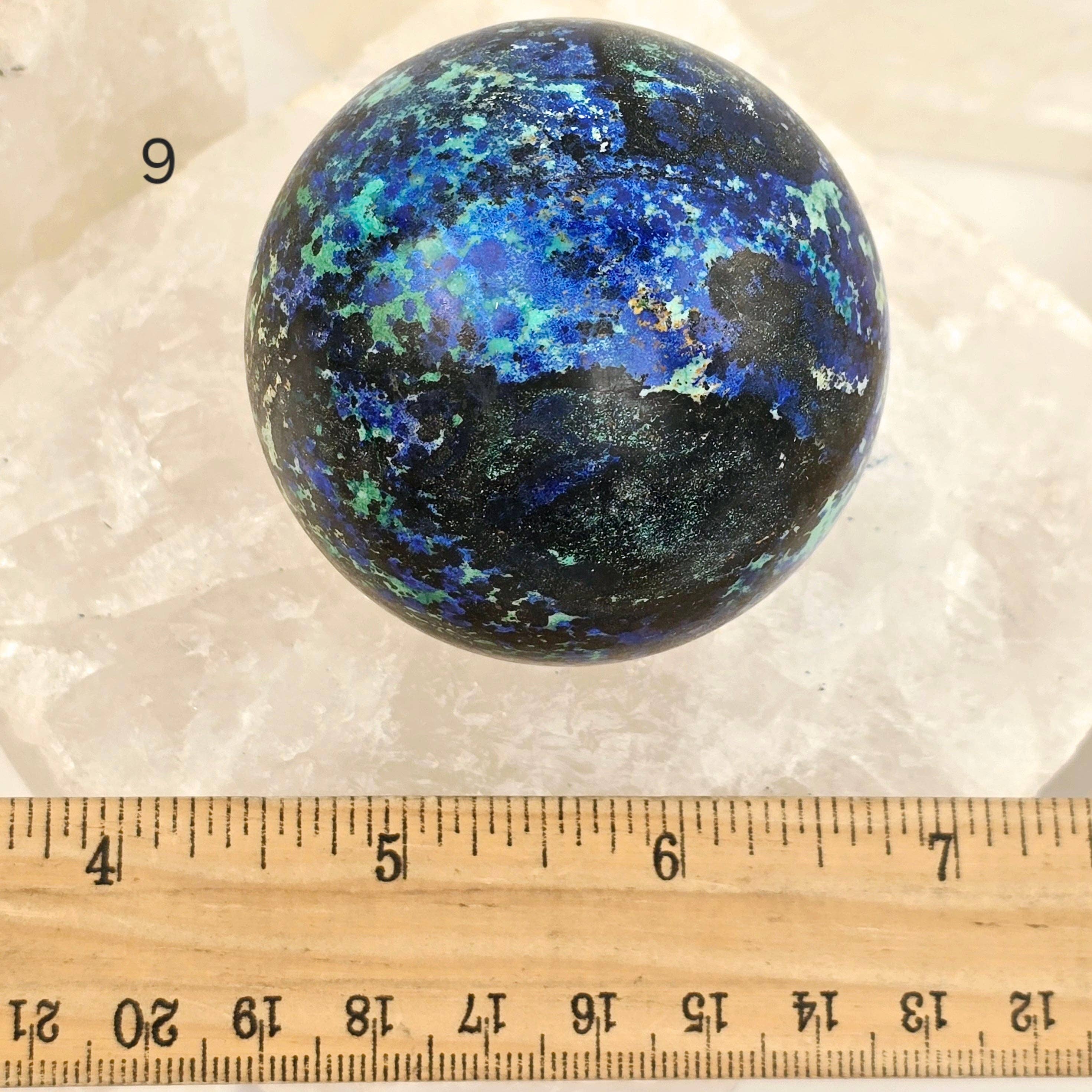 Multicolored spherical object on a white background with a ruler for scale.