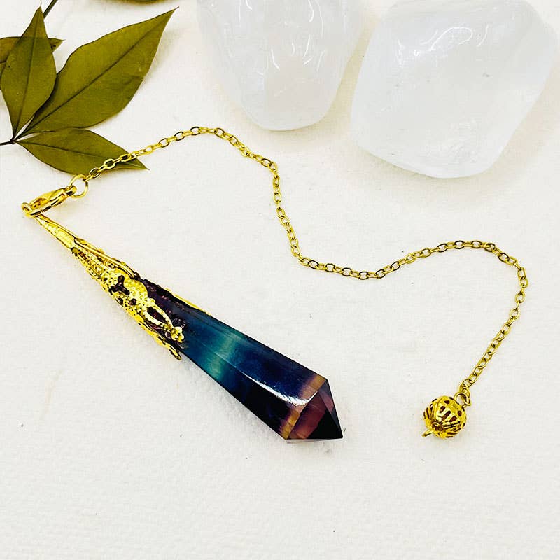 Crystal pendant with gold chain on a white surface with leaves