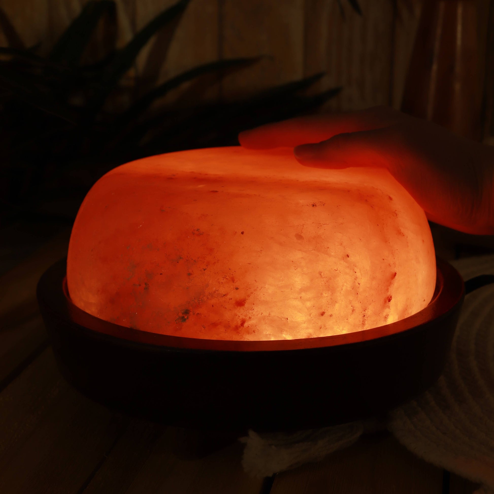 Himalayan salt lamp being held in a hand with a dark background