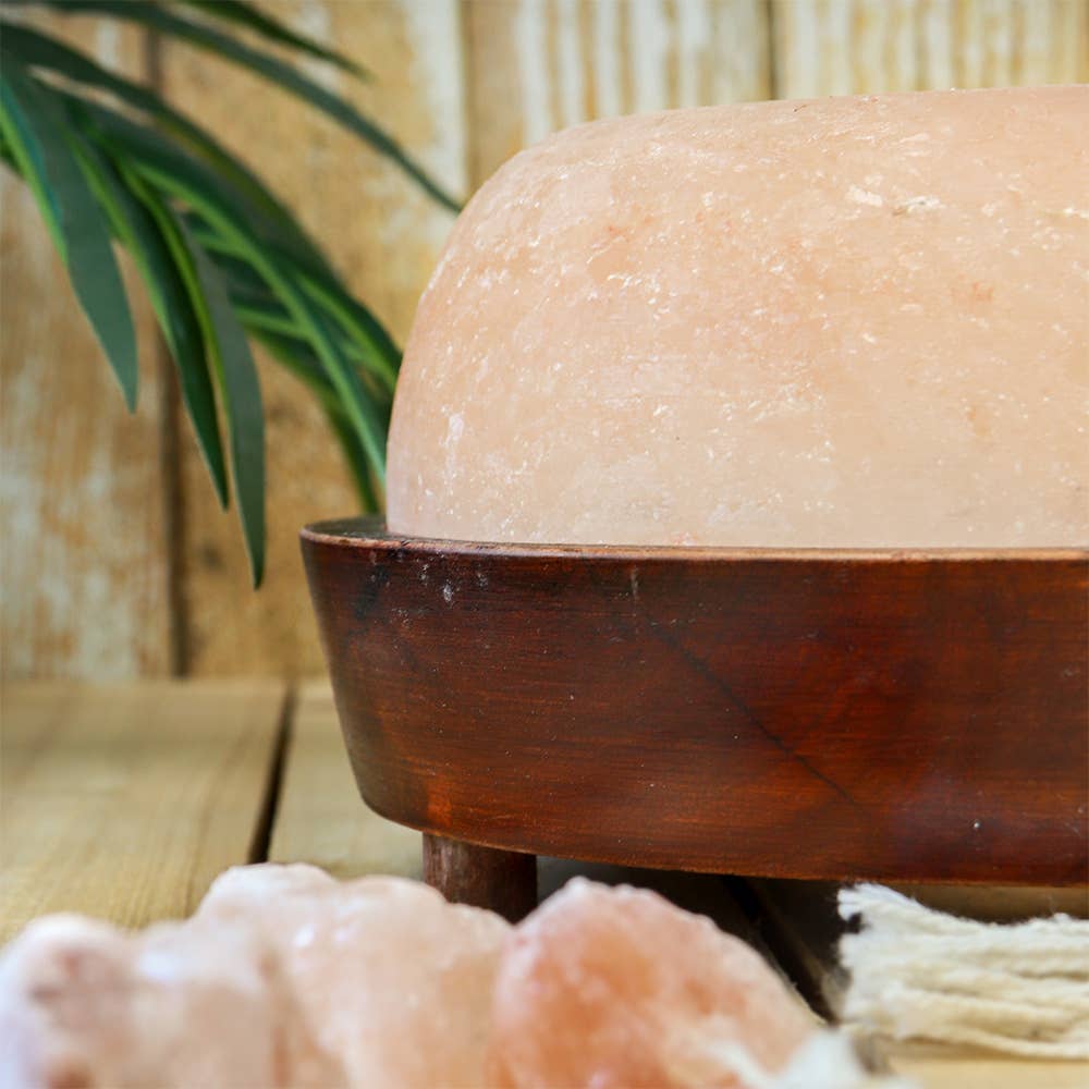Himalayan salt lamp on a wooden base with a blurred background