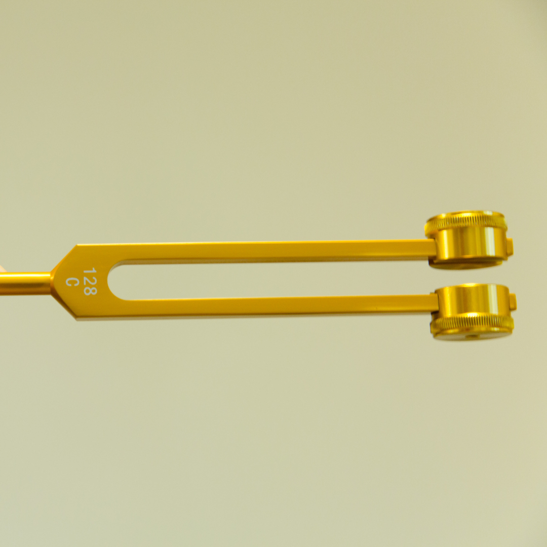 Gold tuning fork on a beige background - JOY - Journey Of You - Spiritual, Holistic, Empowering