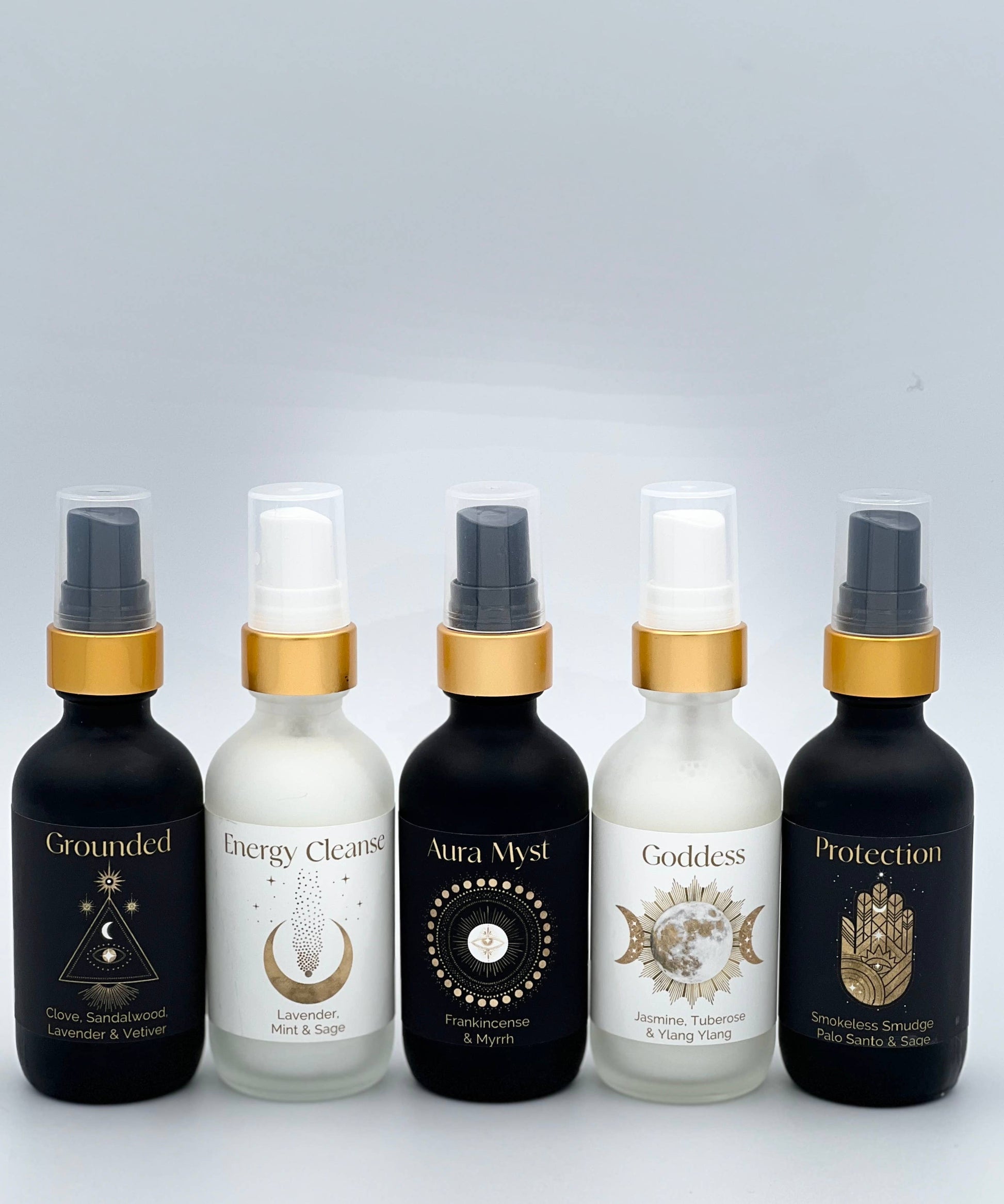 Five bottles of essential oils with gold caps on a light gray background