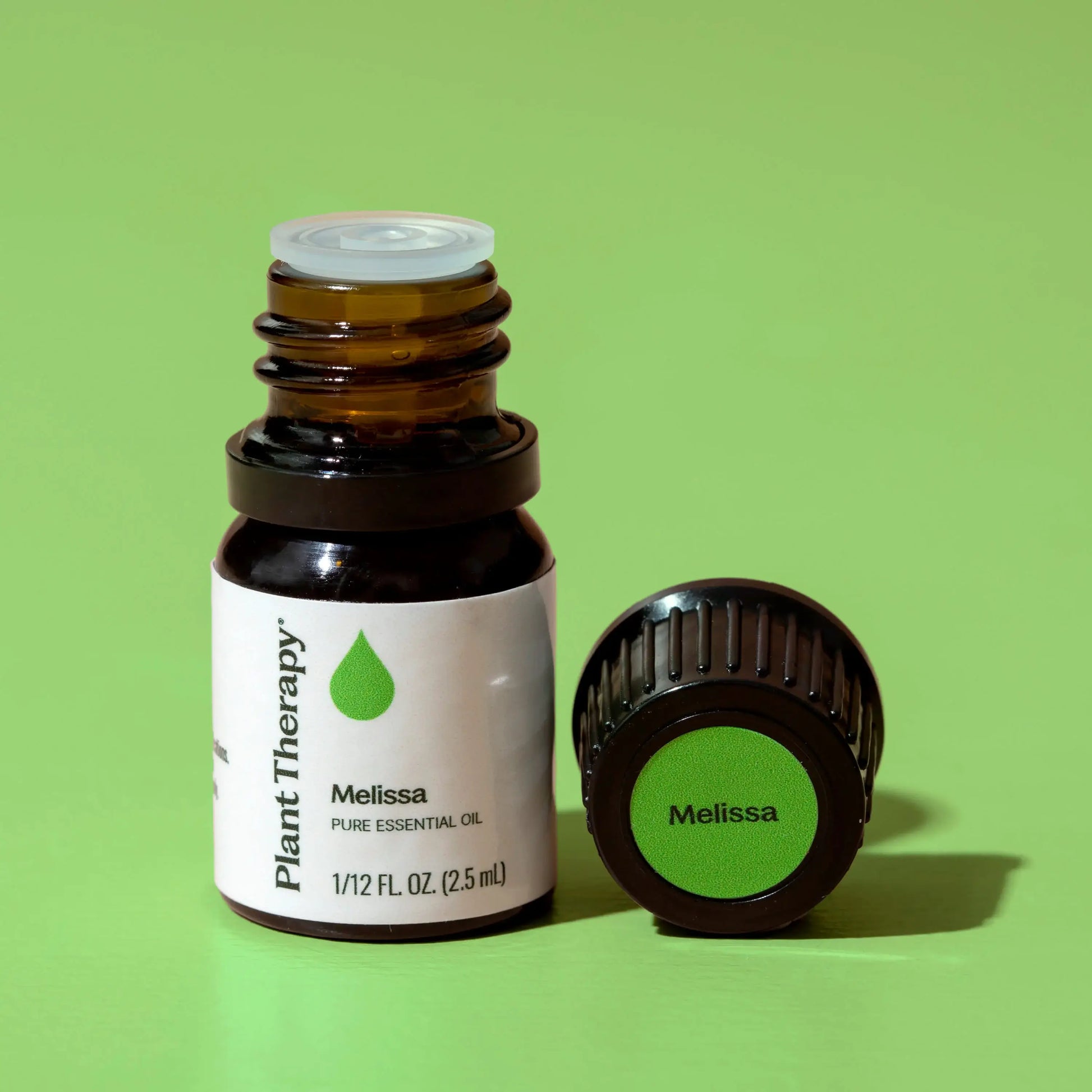 Melissa essential oil bottle with cap on a green background - JOY - Journey Of You - Spiritual, Holistic, Empowering