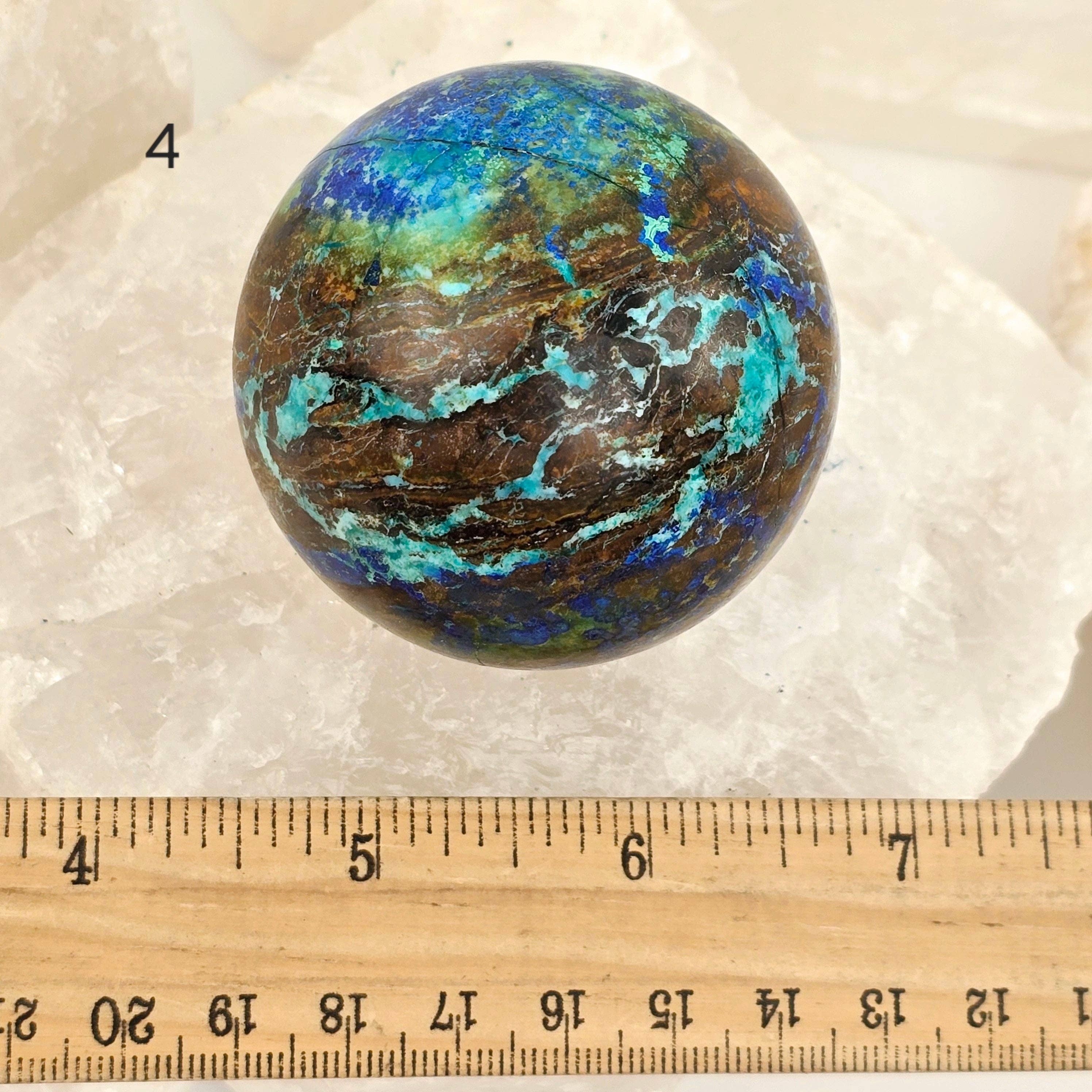 Multicolored spherical stone with a ruler for scale on a white background