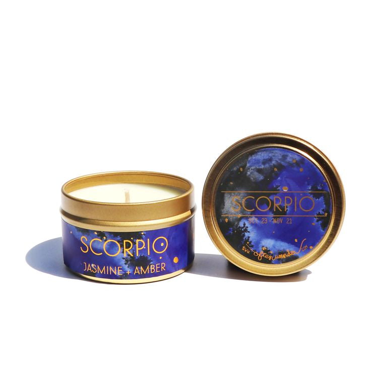 A blue candle with 'Scorpio' and 'Jasmine Amber' labeled on it, placed next to its lid which has a starry pattern - JOY - Journey Of You - Spiritual, Holistic, Empowering